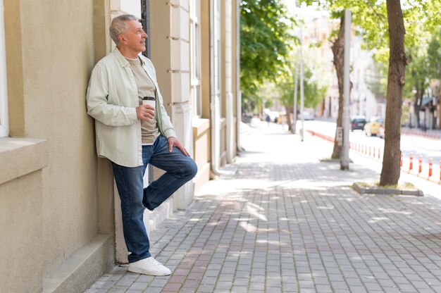 Elderly holding coffee cup full shot