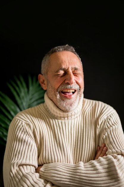 Elderly male with crossed arms laughing