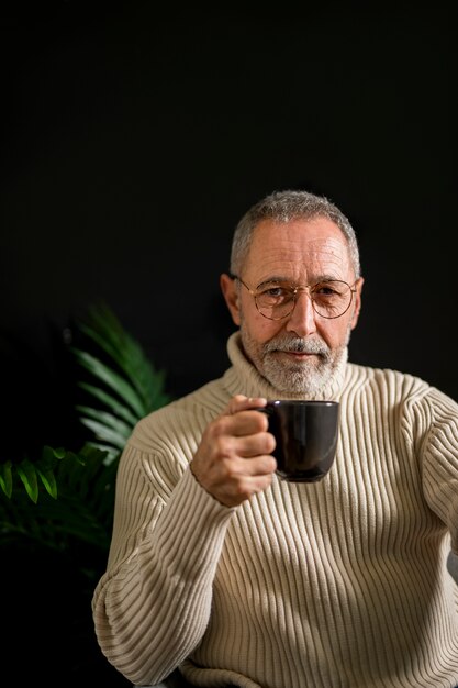 Elderly man in glasses with hot drink