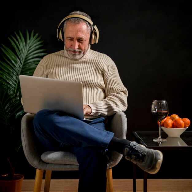 Elderly man in headphones watching movie on laptop