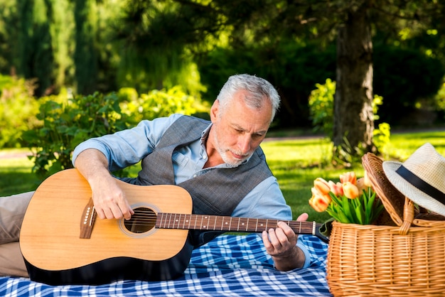 Elderly man playing guitar at the picnic