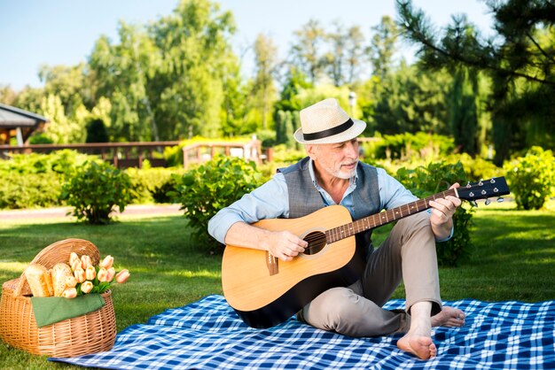 Elderly man playing on guitar