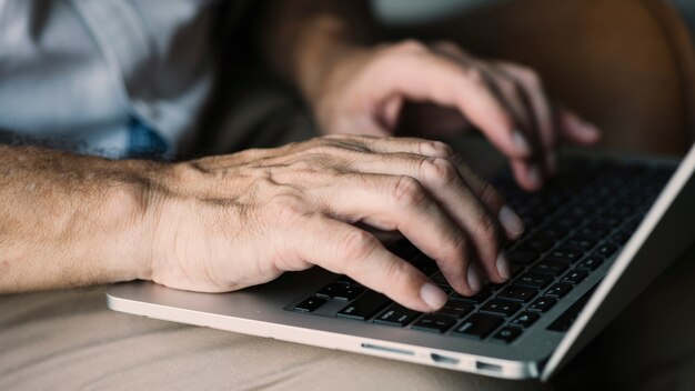 An elderly man's hand typing on laptop