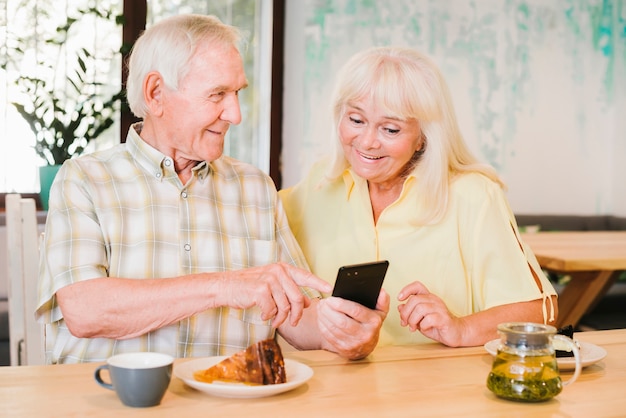 Elderly man showing smartphone to woman