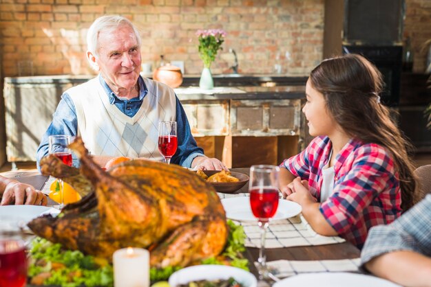 Elderly man sitting at table near girl