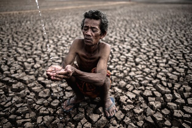 An elderly man sitting in touch with rain in the dry season, global warming, selection focus