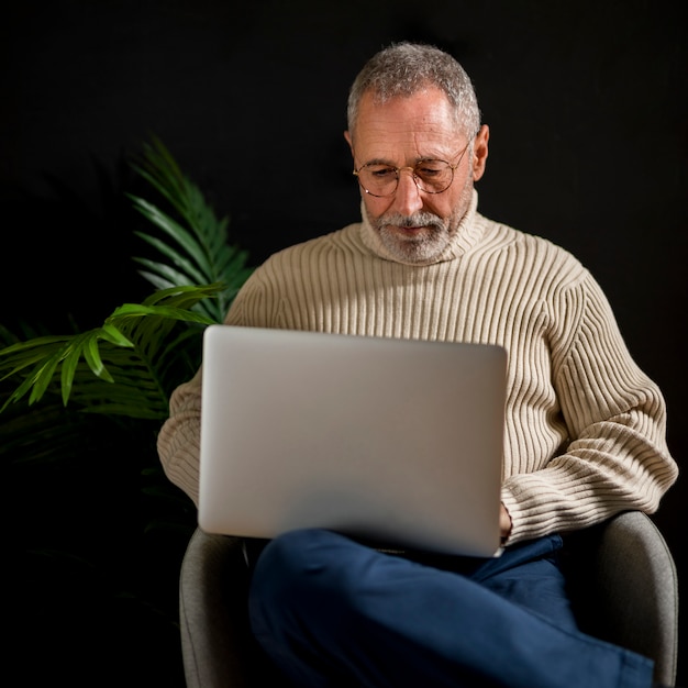 Elderly man using laptop in armchair