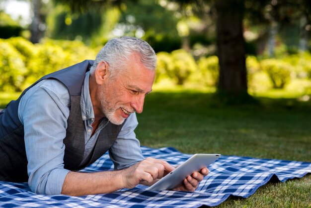 Elderly man using a tablet at the nature