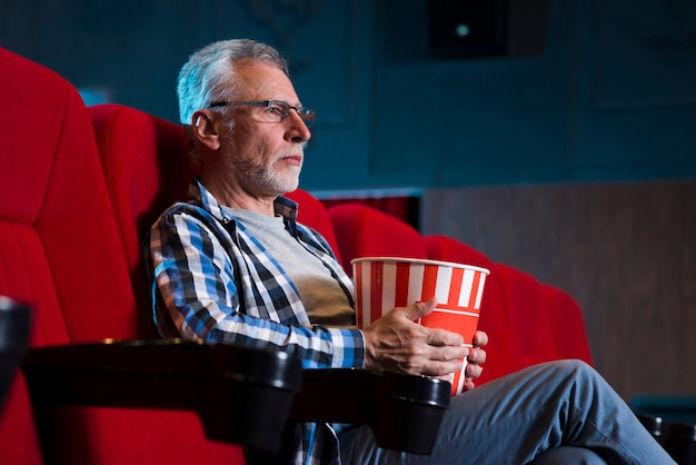 Пожилой мужчина смотрит фильм в кино