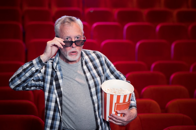 Пожилой мужчина смотрит фильм в кино