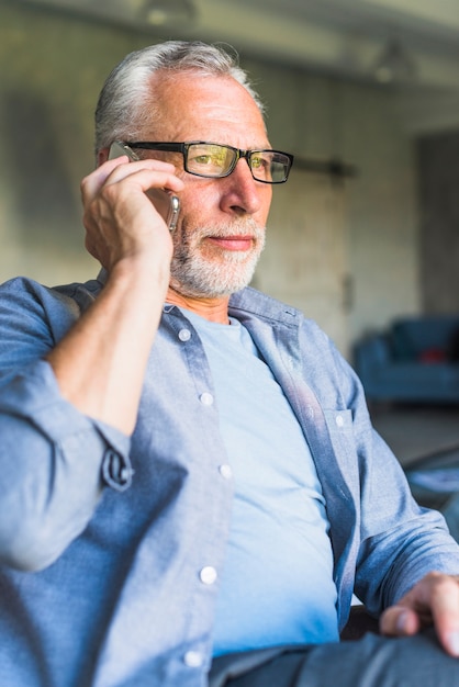 Elderly man wearing black glasses talking on cellphone
