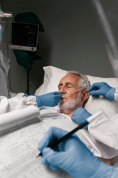 Uomo anziano con respiratore accanto ai medici