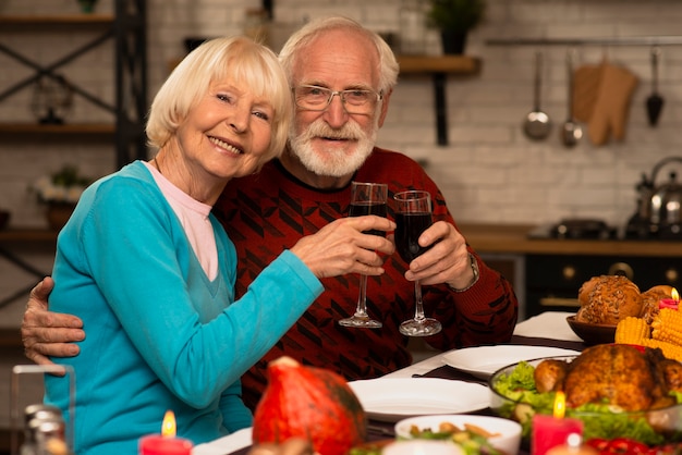 Elderly married couple toasting glasses and looking at camera