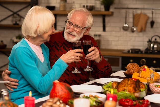 Free photo elderly married couple toasting glasses and looking at each other