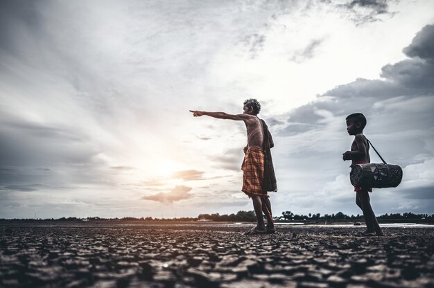 Elderly men and boy find fish on dry ground, global warming