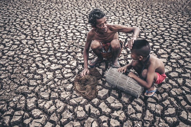 Free photo elderly men and boy find fish on dry ground, global warming