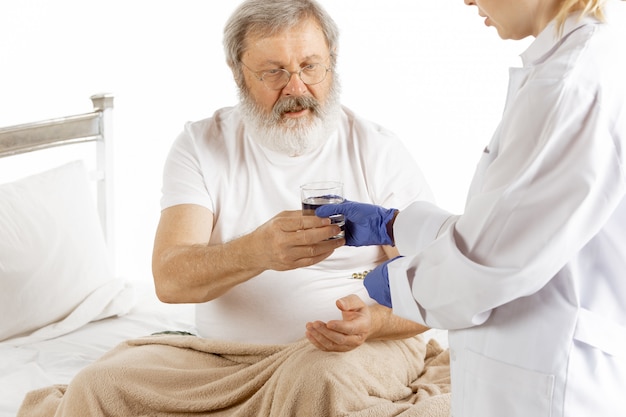 Elderly old man recovering in a hospital bed isolated on white