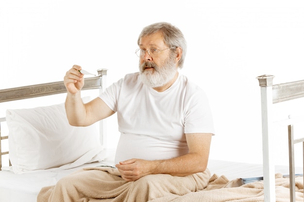 Elderly old man recovering in a hospital bed isolated on white