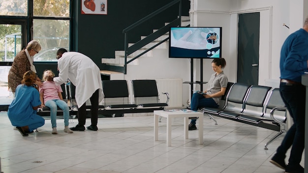 Free photo elderly people taking sick niece to emergency checkup, feeling dizzy and light headed. young child being unconscious in hospital reception, physician consulting girl with flashlight.