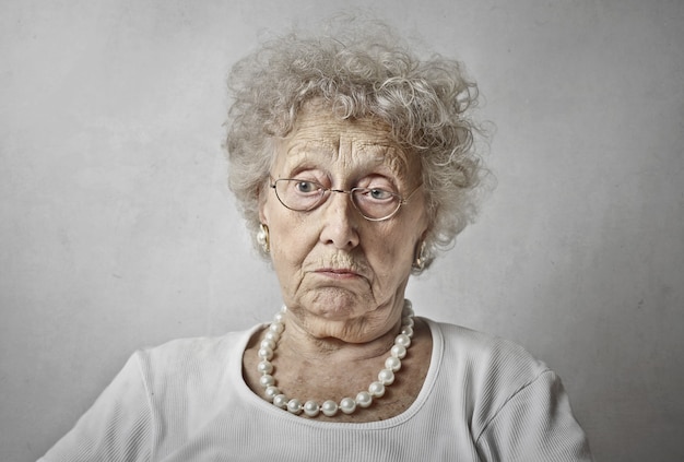 Elderly woman against a white wall with a blank stare