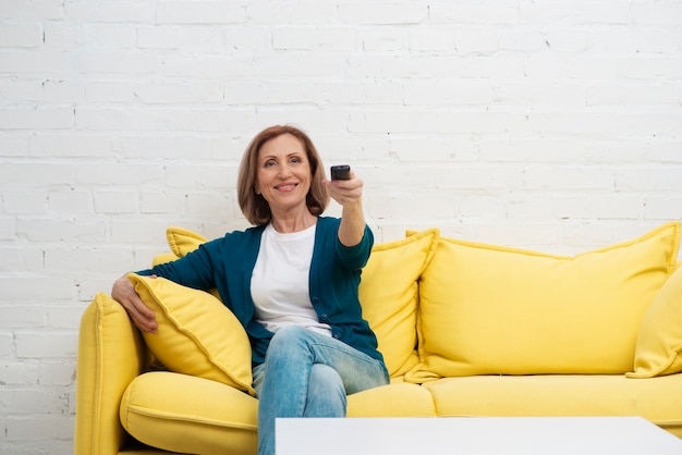 Free photo elderly woman changing television channels