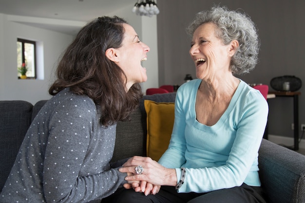 Elderly woman and daughter laughing and holding hands