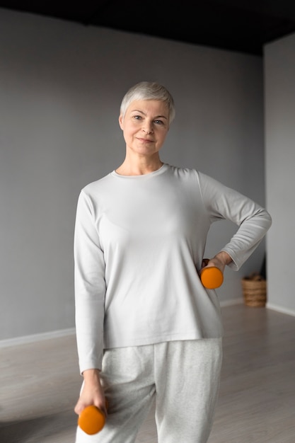 Free photo elderly woman doing dumbbells exercises at the gym