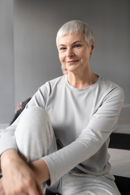 Donna anziana che fa esercizi di fitness in palestra su un tappetino da yoga