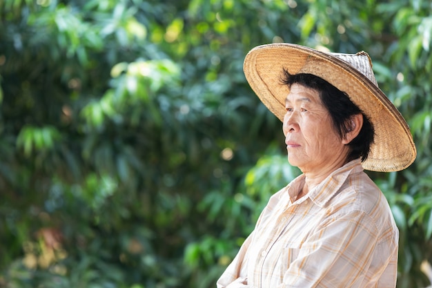 Elderly woman a farmer smiling and holding  in garden.