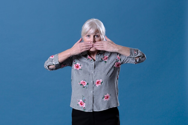 Free photo elderly woman holding hands in front of mouth