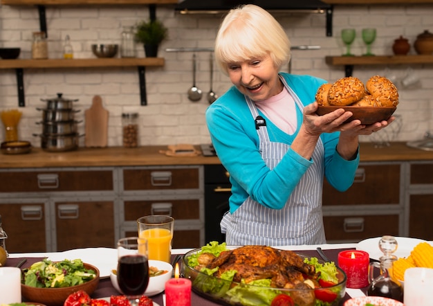 Elderly woman holding a plate with bun bread 