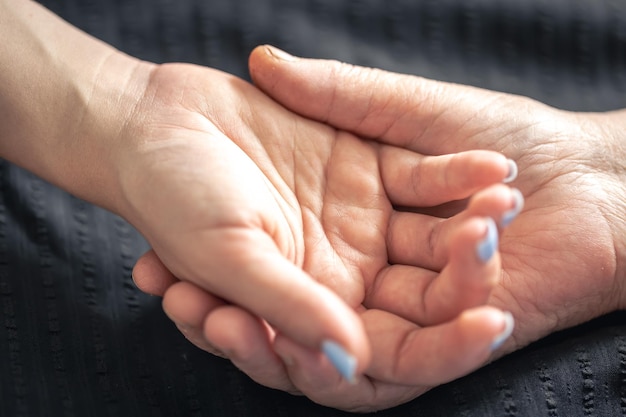 Free photo an elderly woman holds the hand of a young woman closeup