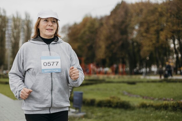 Elderly woman jogging outdoors with copy space