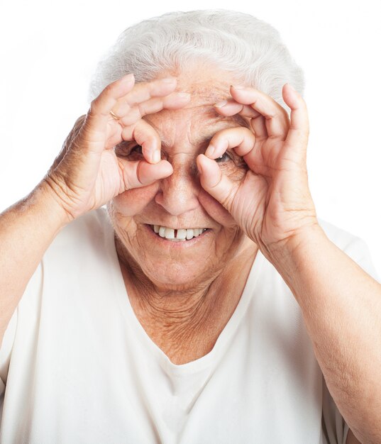 Пожилая женщина делает очки с ее пальцами