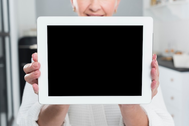 Elderly woman posing while holding tablet