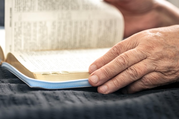 An elderly woman reads a book of the bible hands and closeup