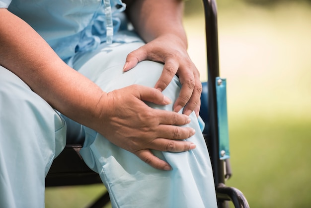 무릎 통증으로 휠체어에 앉아있는 노인 여성