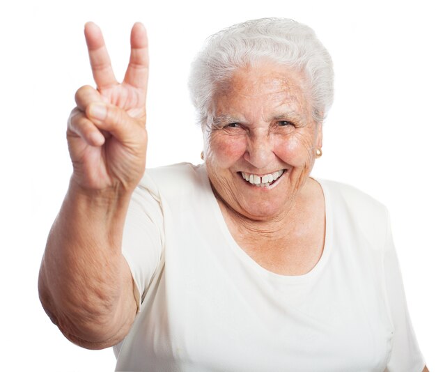 Elderly woman smiling with two raised fingers