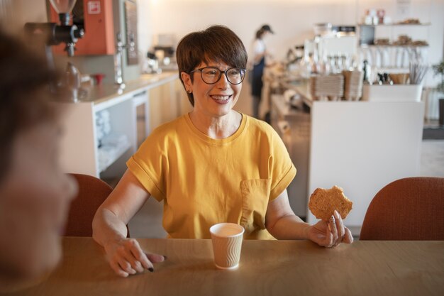 Elderly woman talking with friends and drinking coffee