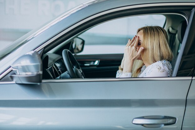 Пожилая женщина тестирует автомобиль в автосалоне