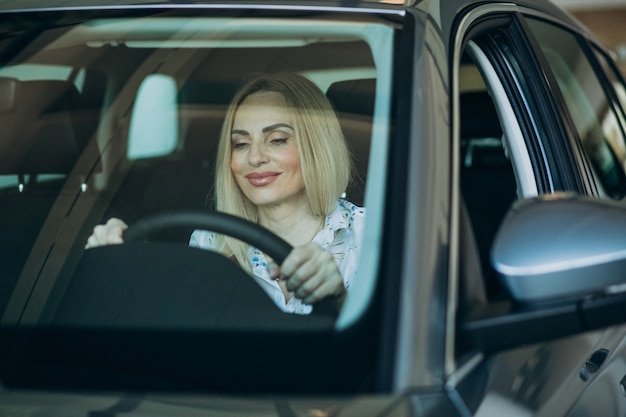 Elderly woman testing a car in car showroom