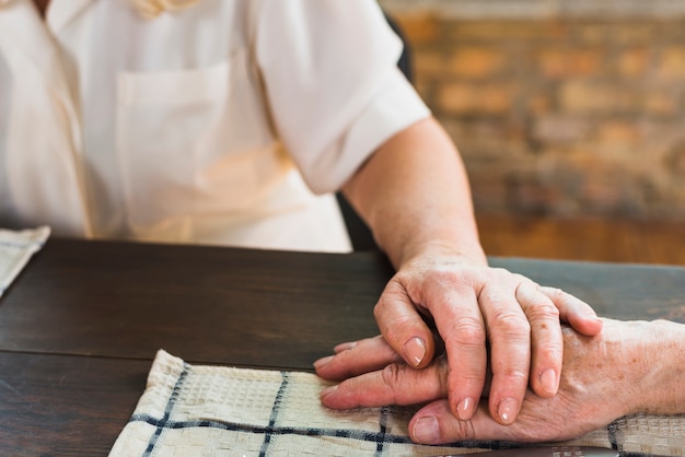 Elderly woman touching hand of husband 