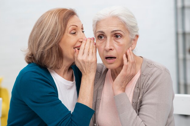 Elderly woman whispering to her friend