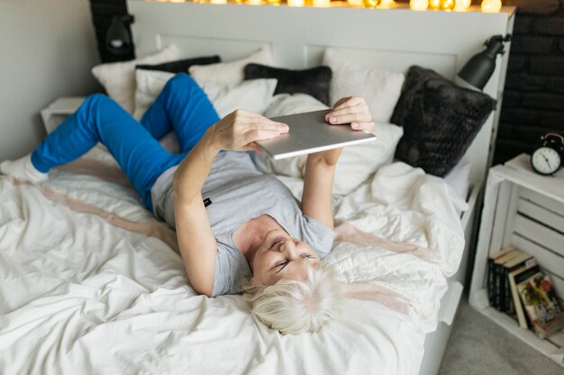 Elderly woman with tablet on bed