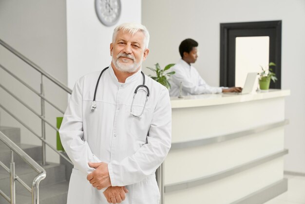 Eldery doctor in coat posing in hospital