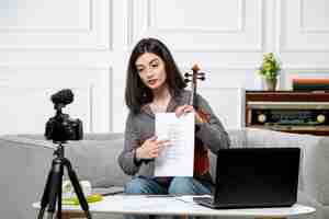 Foto gratuita elearning carina giovane bella ragazza a distanza a casa prendendo lezioni di violino sulla fotocamera