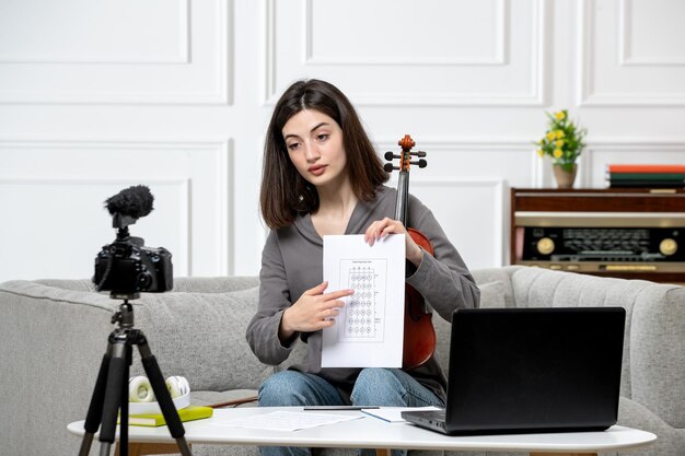 Elearning cute young beautiful girl remotely at home taking violin classes on camera