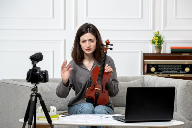 Elearning remotely giving violin classes at home young cute beautiful girl being confused