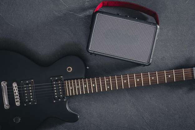 Free photo electric guitar and speaker on a textured black background top view