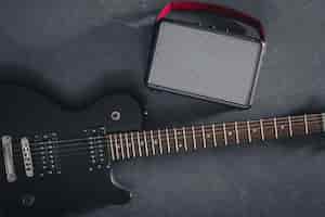 Free photo electric guitar and speaker on a textured black background top view